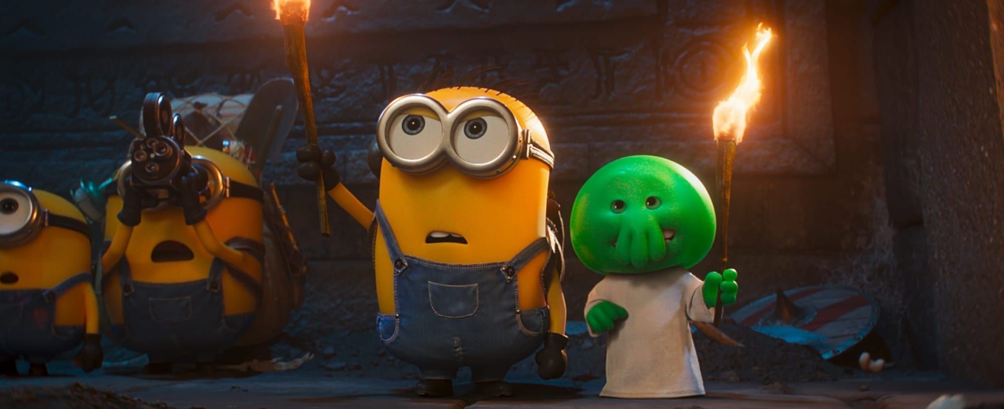 Official teaser graphic for Minions & Monsters showing a group of Minions playfully interacting with fantastical, monstrous creatures.