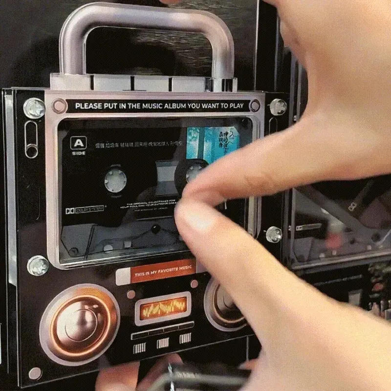 A close-up of a vinyl record being placed on a turntable alongside a collection of vintage cassette tapes on a wooden shelf.