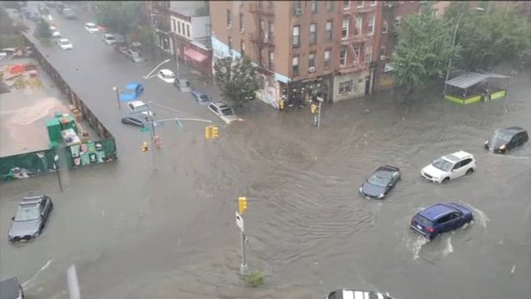 New York City streets underwater during severe flooding with cars surrounded by water.