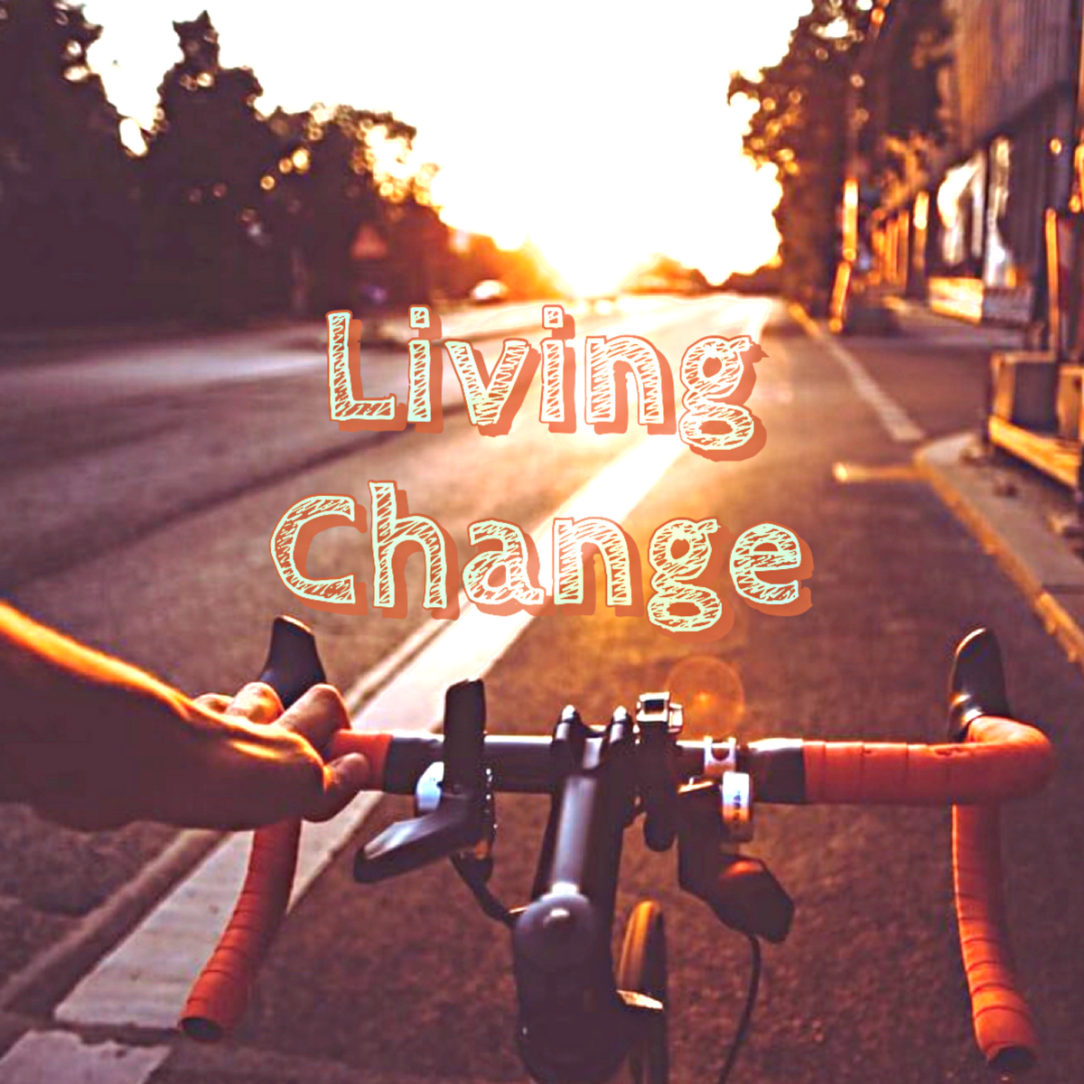 White left hand on bike handlebars with orange grip tape in foreground, with golden hour sunset light on small town street in front of bike 