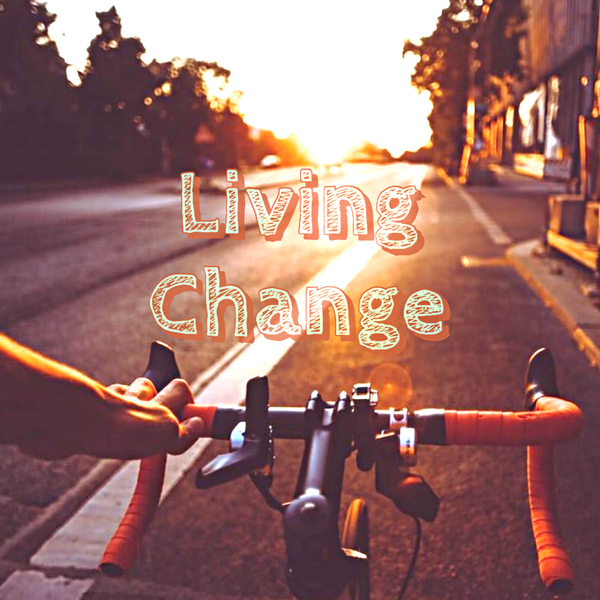 White left hand on bike handlebars with orange grip tape in foreground, with golden hour sunset light on small town street in front of bike