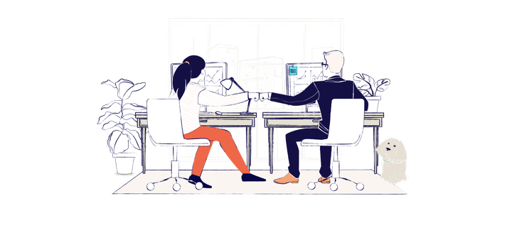 A man and a woman sit at a desk looking at computers, they are fist pumping