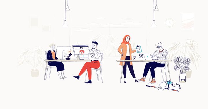 Four workers are sitting around two desks. A service dog sits below one desk.