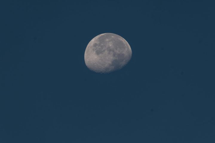 grey waning gibbous moon on a grey-blue sky