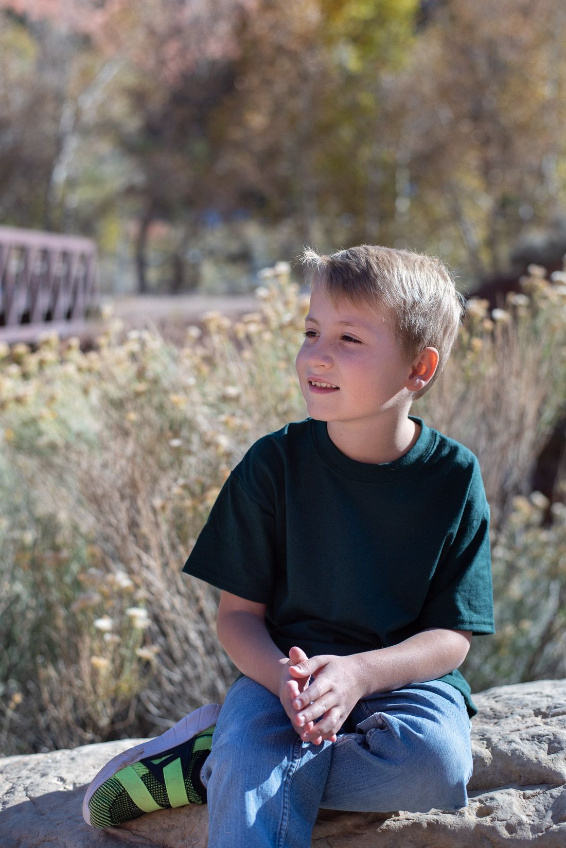 Boy in green shirt sitting on a rock and looking to the right-Bethany Allen Photography