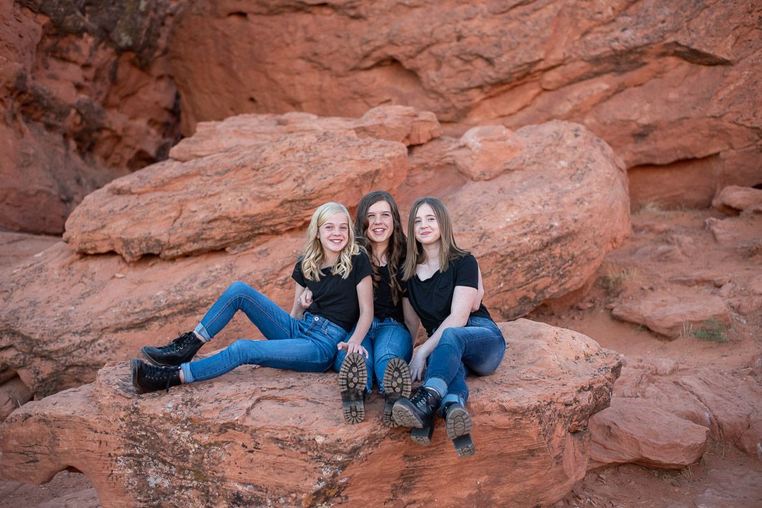 3 teenage sisters sitting on red rocks in St. George