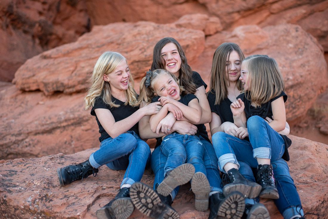 5 sisters sitting on a rock and laughing together