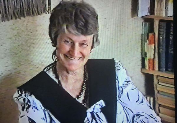 A still from a 1980s home video, featuring an older woman with short grey hair grinning at the camera