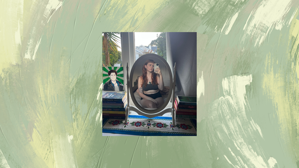 A photograph of me, sitting in front of a mirror, in a grey bra and black boxers. The sun is out. Behind the photograph is a streaky painted green background.