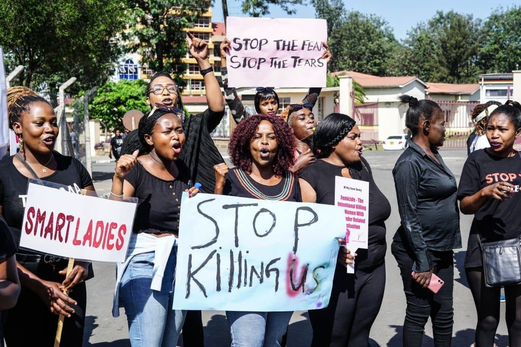 Black femmes with signs protesting femicide. 