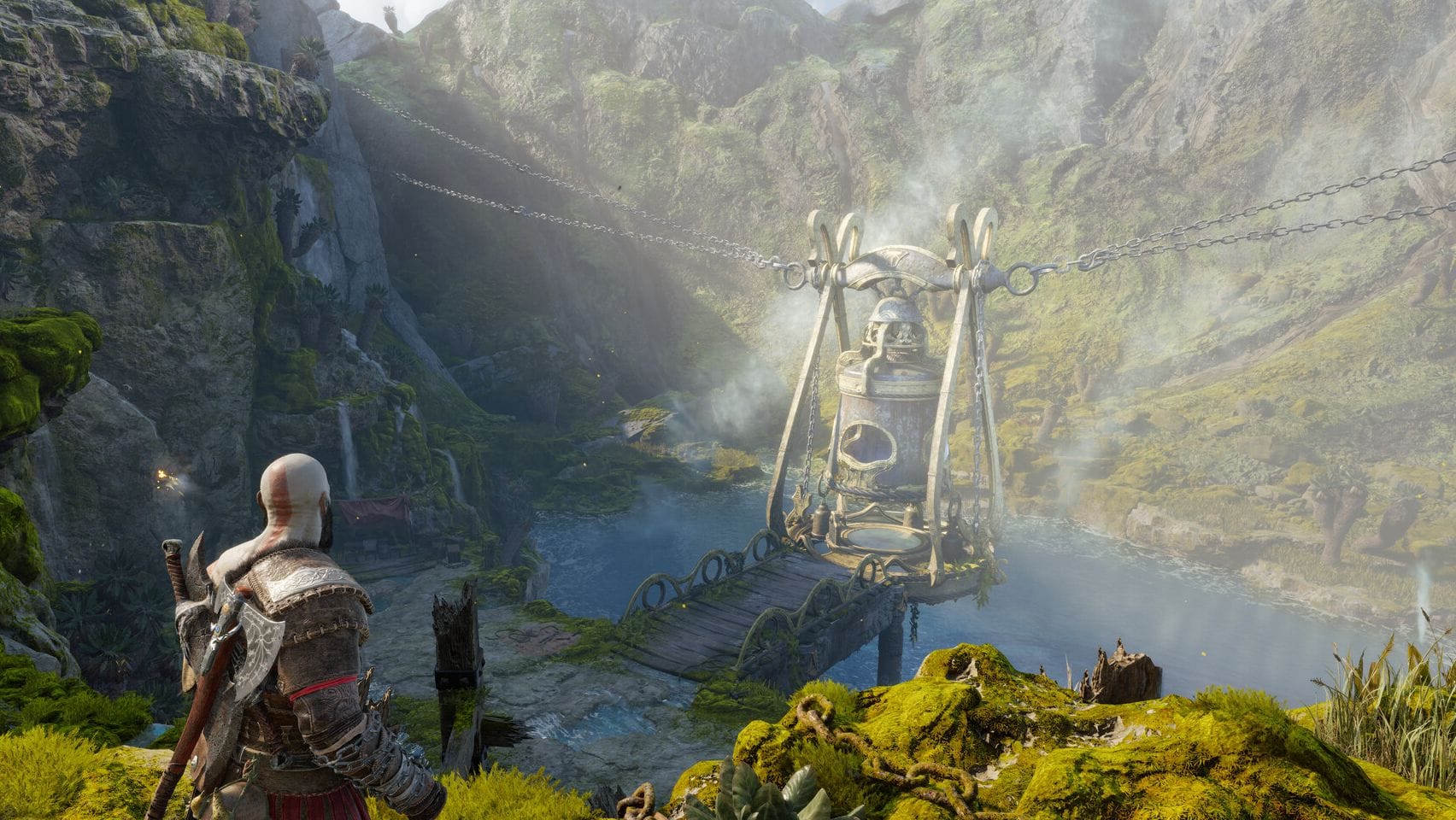Kratos from God of War looks down at a large bell-like device hanging from chains.