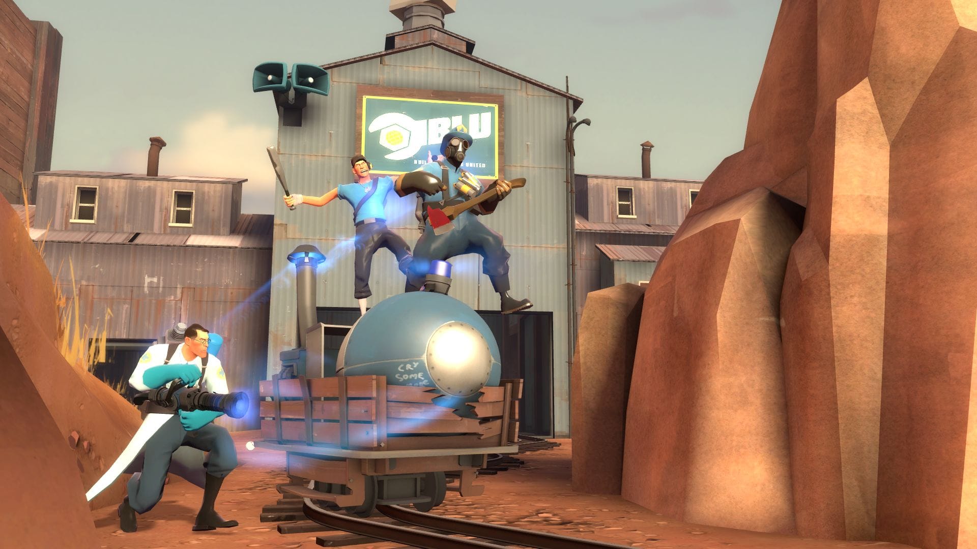 Three players ride the mine cart through a canyon in Team Fortress 2.