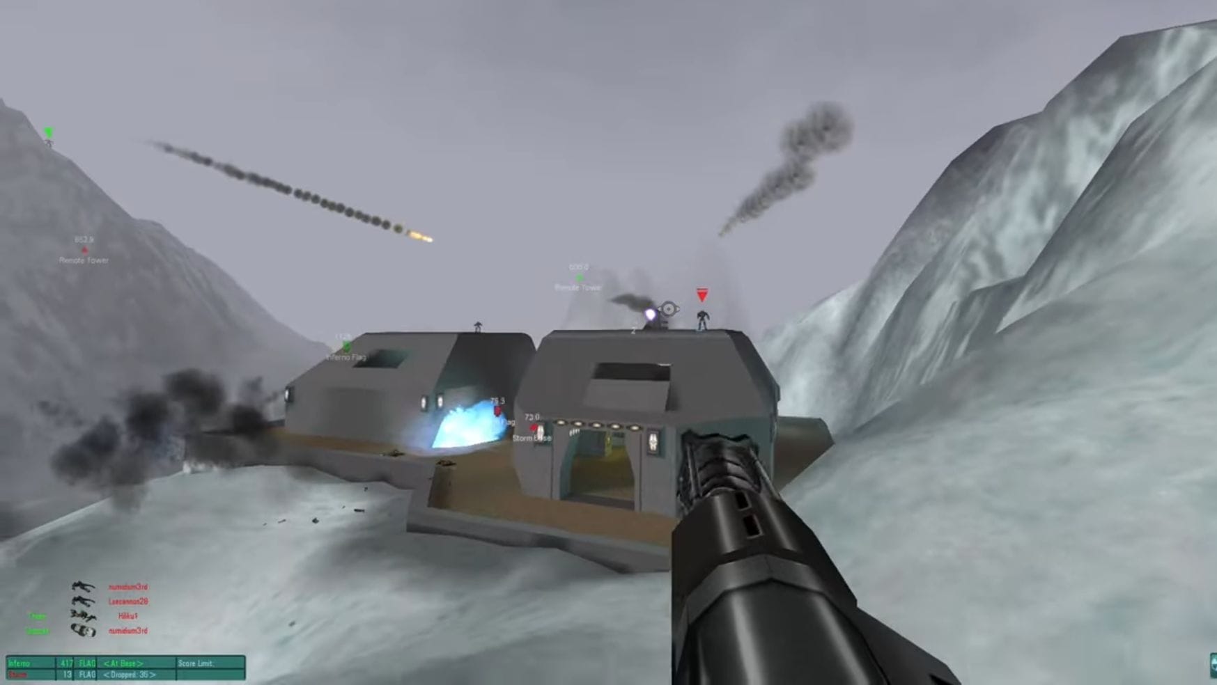 The player points a gun at the enemy base, surrounded by snowy mountains.