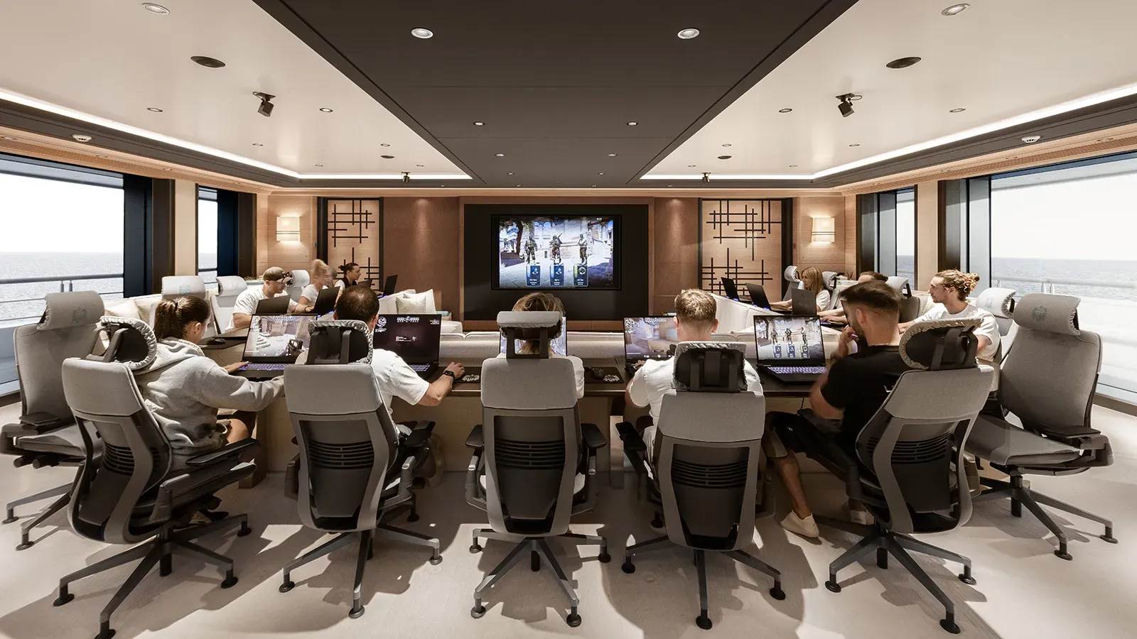 People playing Counter-Strike in a large conference room in a luxury yacht with full-length windows on either side.