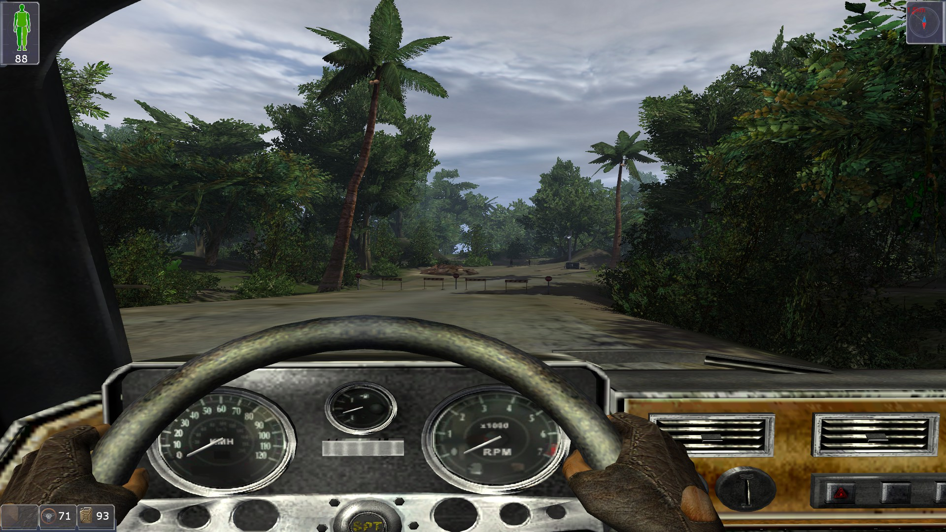 Driving a car in a first-person viewpoint towards a roadblock on a jungle road.