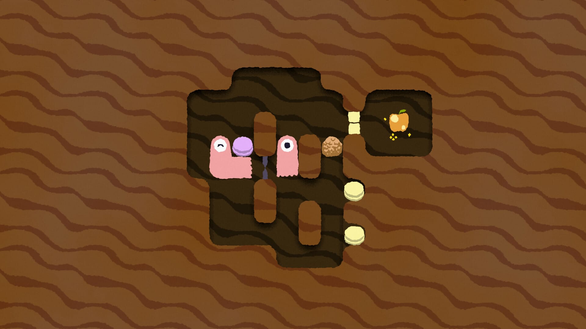 A worm, cut in half, in a grid of dirt. There's a rock, a golden apple and two buttons.