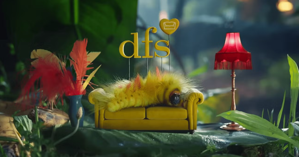 A still from a DFS TV advertisement showing a fluffy caterpillar lying on a sofa, with DFS branding above.