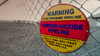 A warning sign for a carbon dioxide pipeline hangs on a chain-link fence.