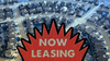 In a composite image, an aerial view of a suburban neighborhood is seen behind a “Now Leasing” sign.