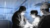 An edited image of surgeons at work in an operating room with a stylized heart-rate graphic in the background.