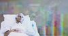 An edited image of a man in a hospital bed with upward-trending graph graphics in the background. (Canva; edited)