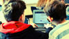 An edited image of two kids working on a laptop. 