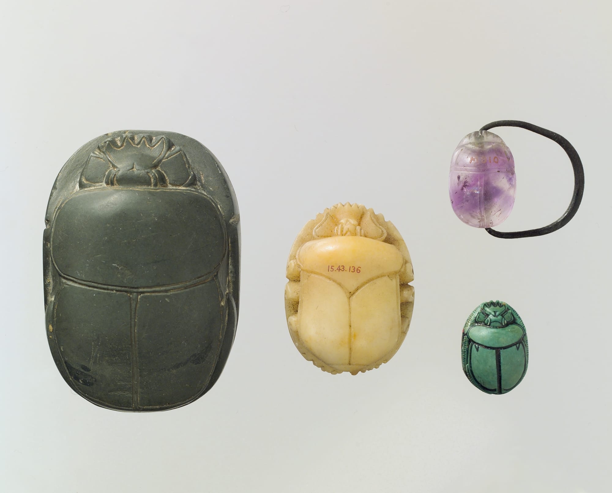 Fotografía de escarabeos egipcios de diferentes materiales y tamaños, usados como amuletos en rituales funerarios. Eran piezas esenciales en el Libro de los Muertos para garantizar la protección y el renacimiento del difunto en el más allá.
