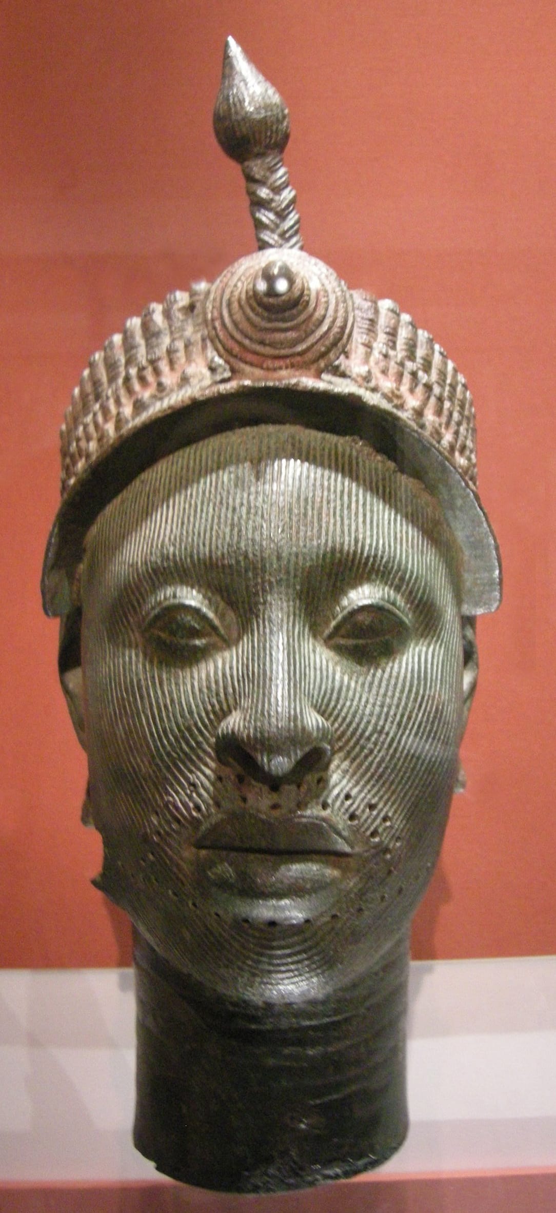 Cabeza escultórica yoruba de Ilé-Ifẹ̀ en metal fundido, con rasgos naturalistas y superficie estriada