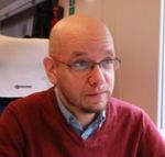 Profile picture of Gabor, a bald white man with glasses, light beard and inquisitive expression. He's wearing a red sweater over a blue shirt. 