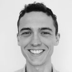 Black and white profile picture of Joe, a young white man with a wide smile, dimples and short hair.