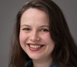 Profile picture of Blossom, a white woman in her twenties, with an open smile and long dark hair. She has engaging eyes, and wears a denim jacket.