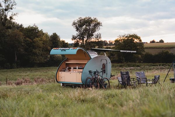 Gehuurde teardrop minicaravan met luifel en stoelen in een weide