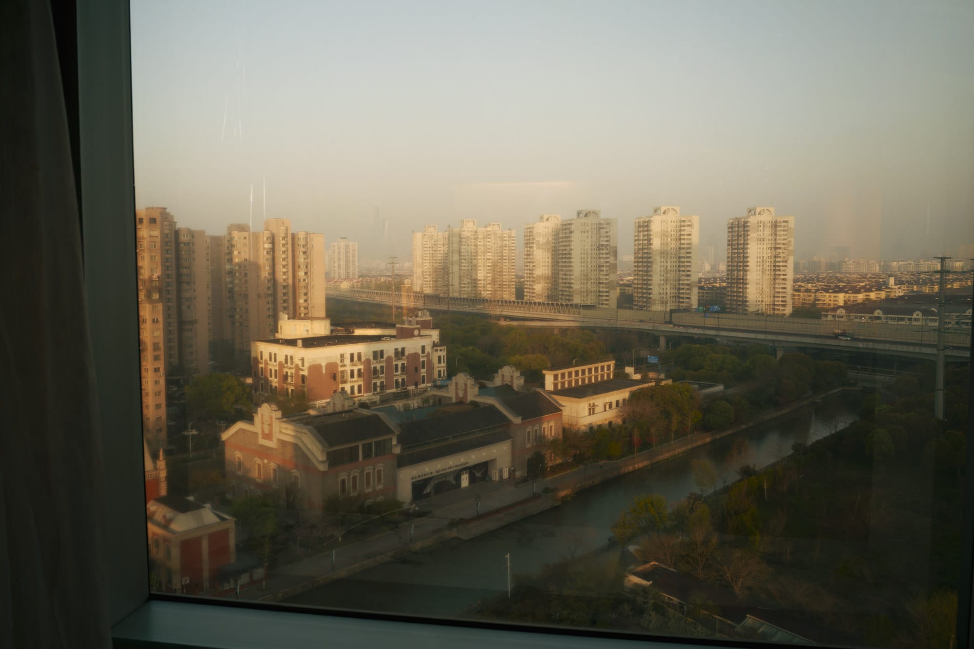 Mix of buildings out hotel window, tall skyscrapers faintly visible in background fog.