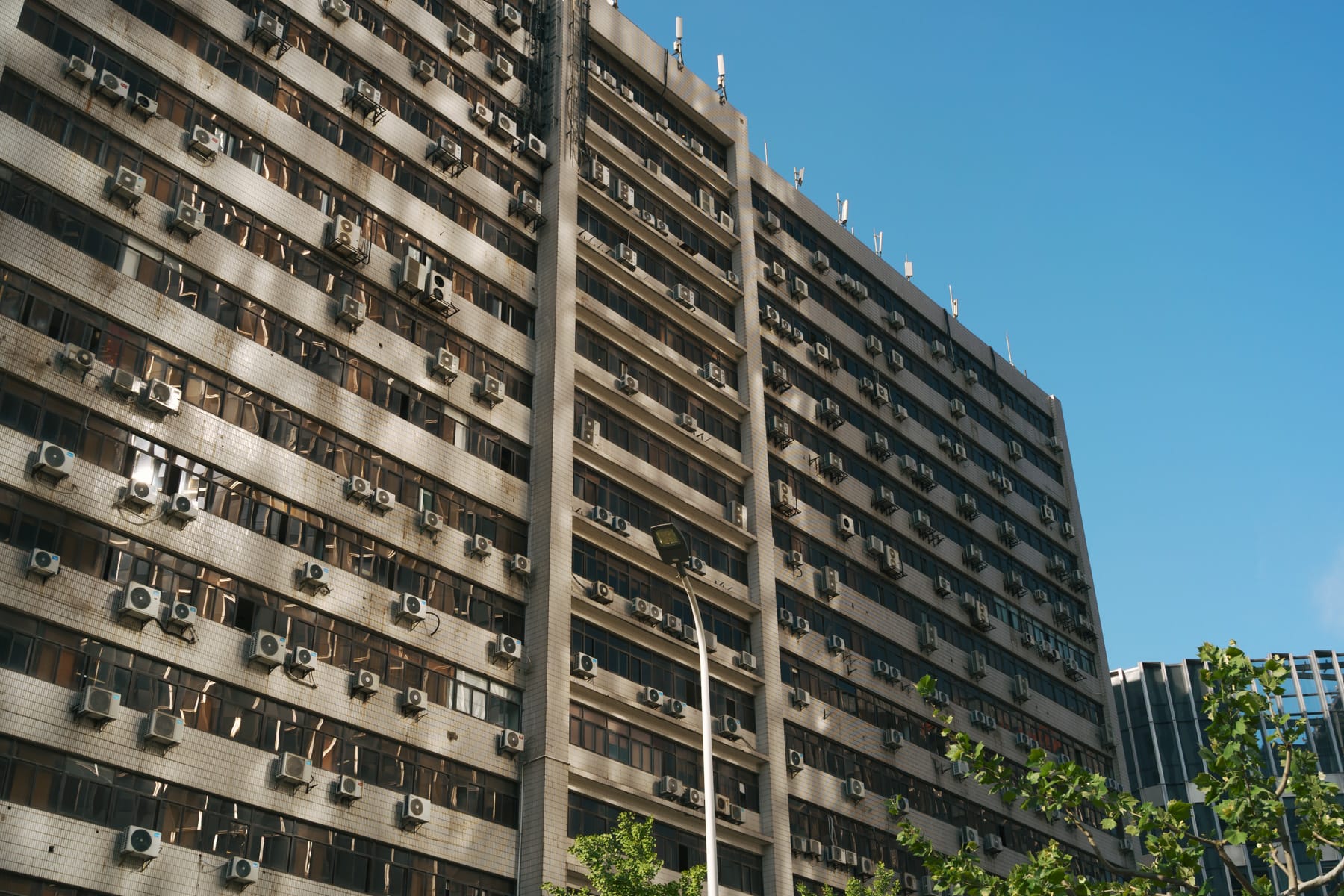 Heat pump ACs studded off tall, horizontal apartment building.