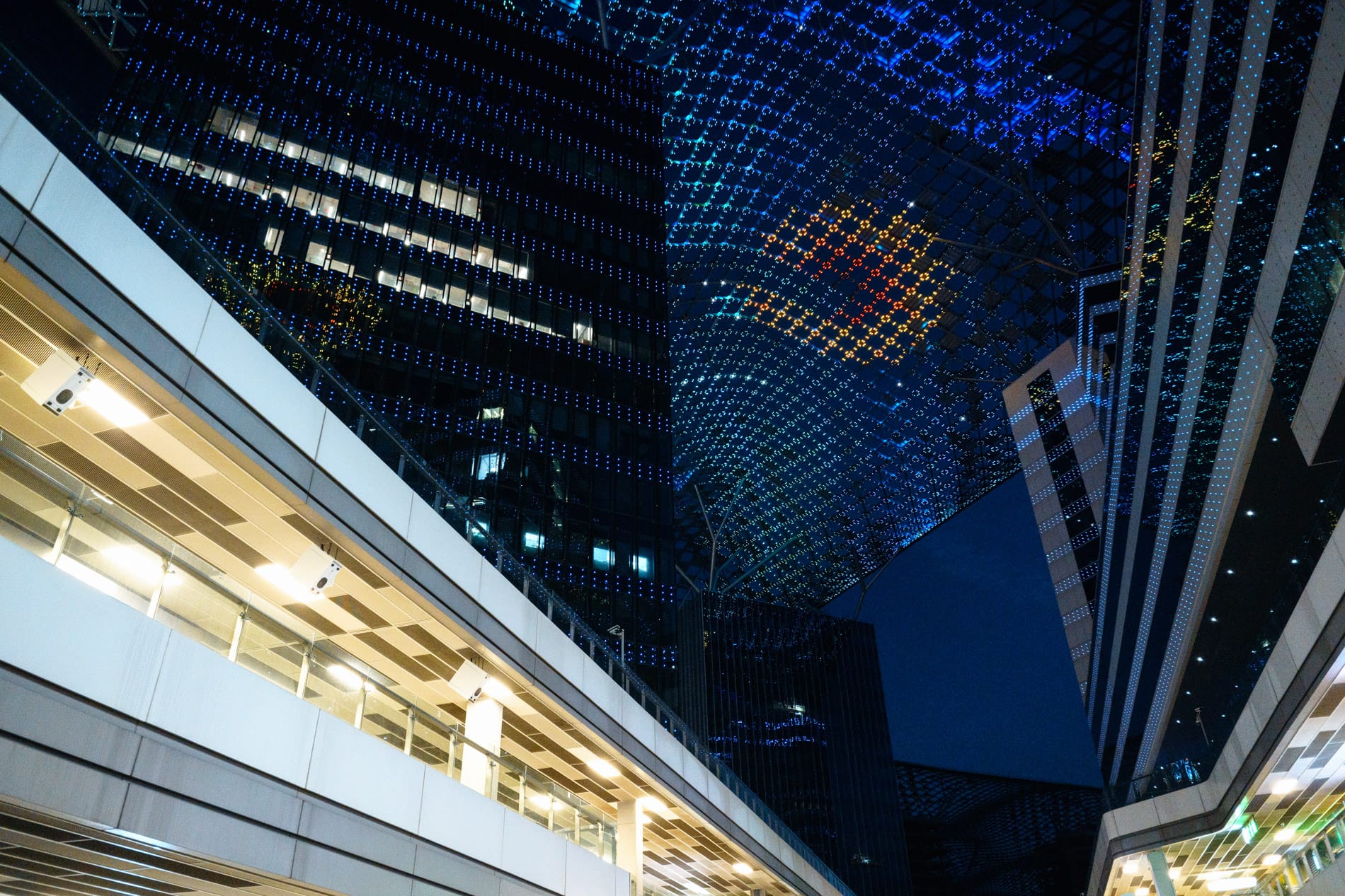 Modern shopping area at night with led grid over sky