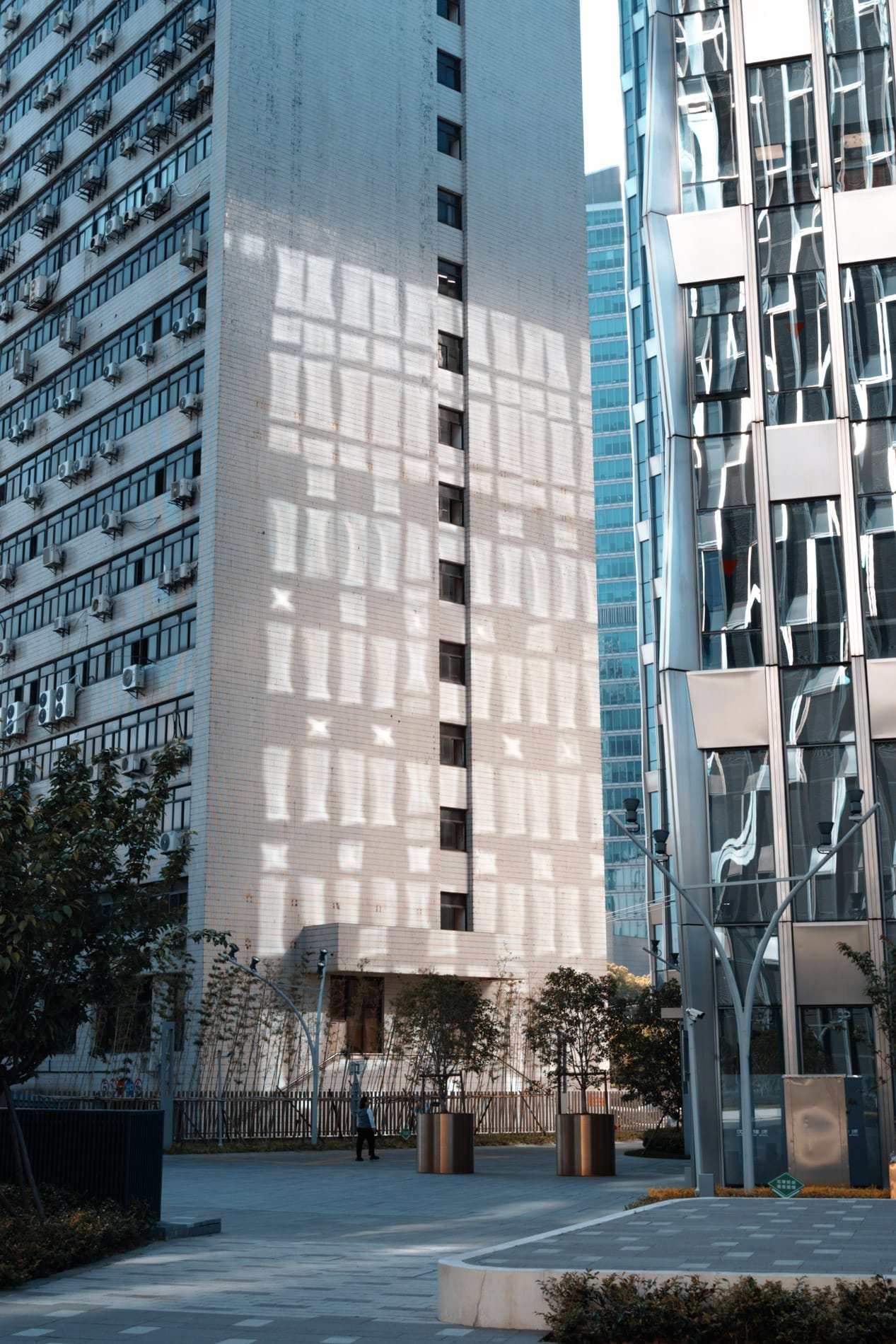 Reflected sun off modern skyscraper windows form quilt of light on adjacent building.