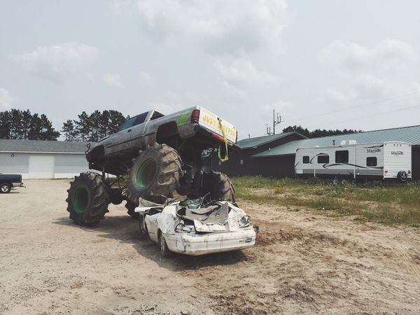 Monster truck mid-crush on old white car. Some kind of art installation?