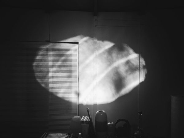 Black and white. Oval oculus-light in shadowy yurt, outlines of vases and closed blinds.