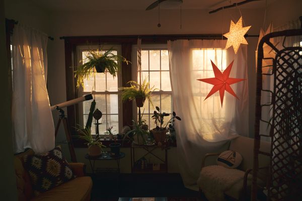 Sunroom at magic hour, warm light through windows and glowing star pendant lights