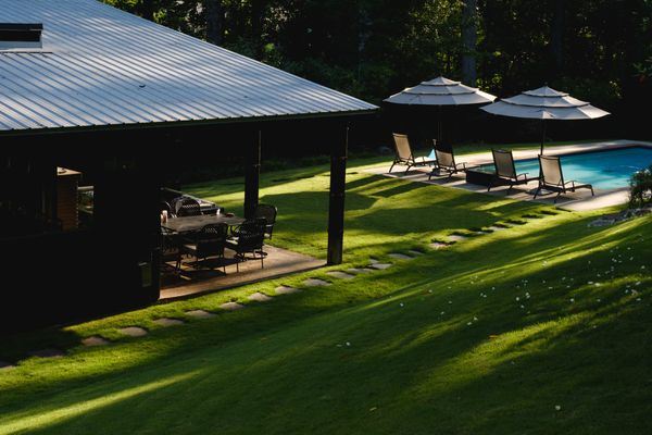 Long morning shadows over back yard with pool and covered patio.
