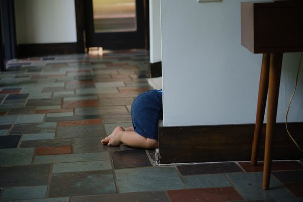 Baby butt sticking out from behind hallway. Red and gray slate tile and mid century furniture.