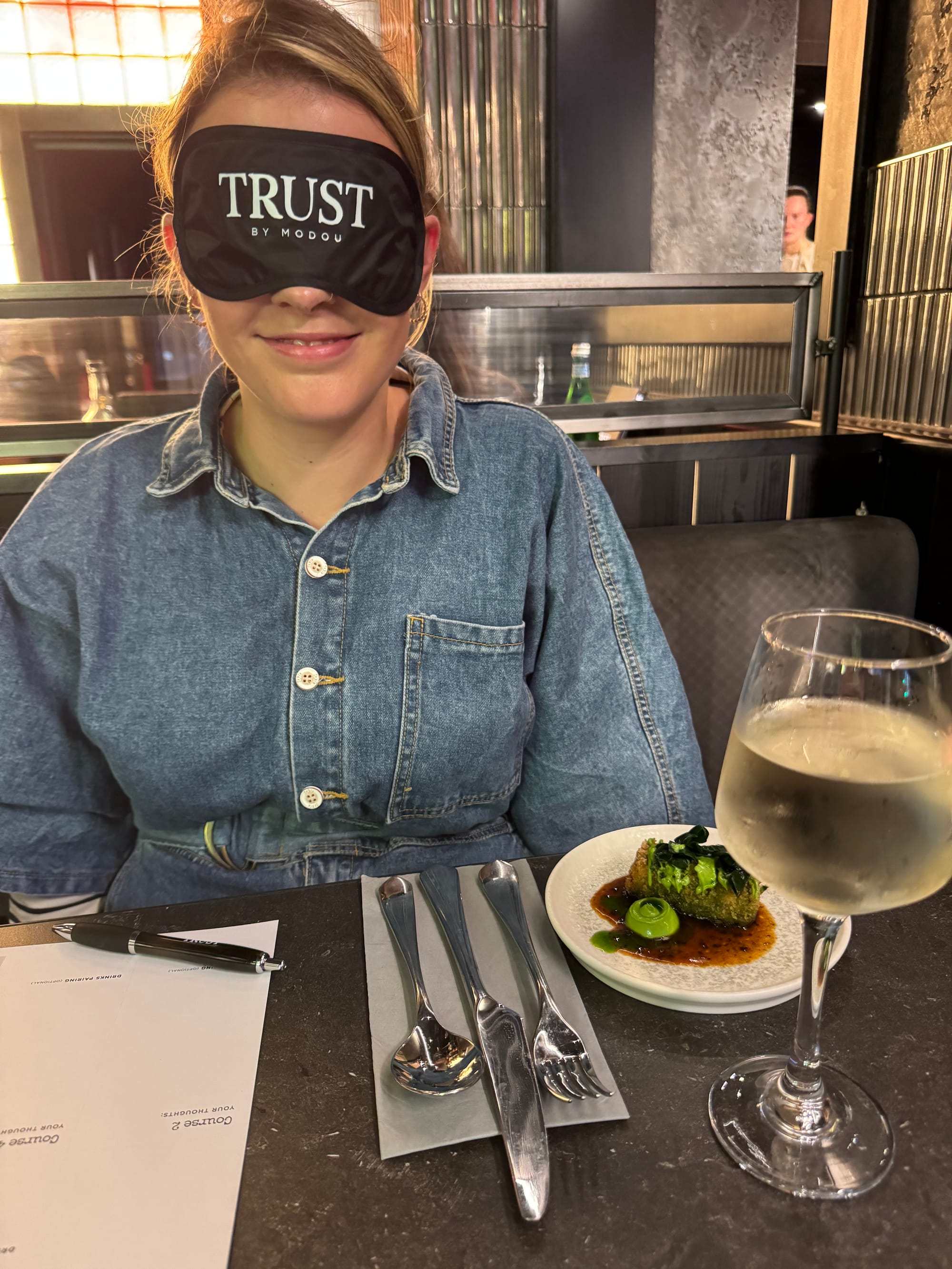 Daniella wearing a blindfold served with the first course .