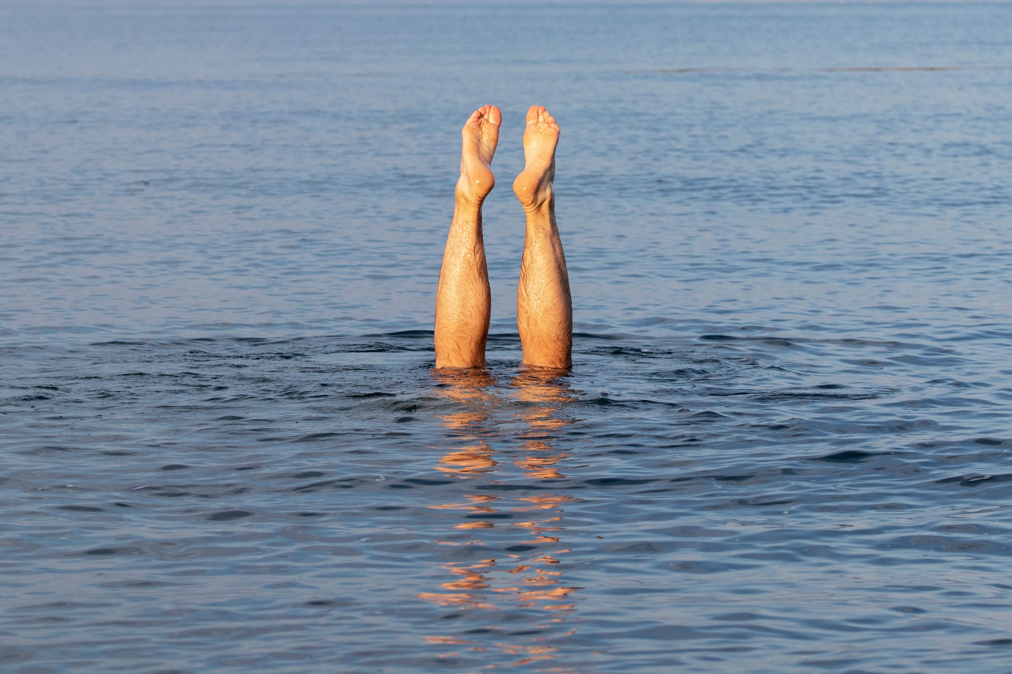 Two legs are visible sticking up from the water as if a person has dived in.