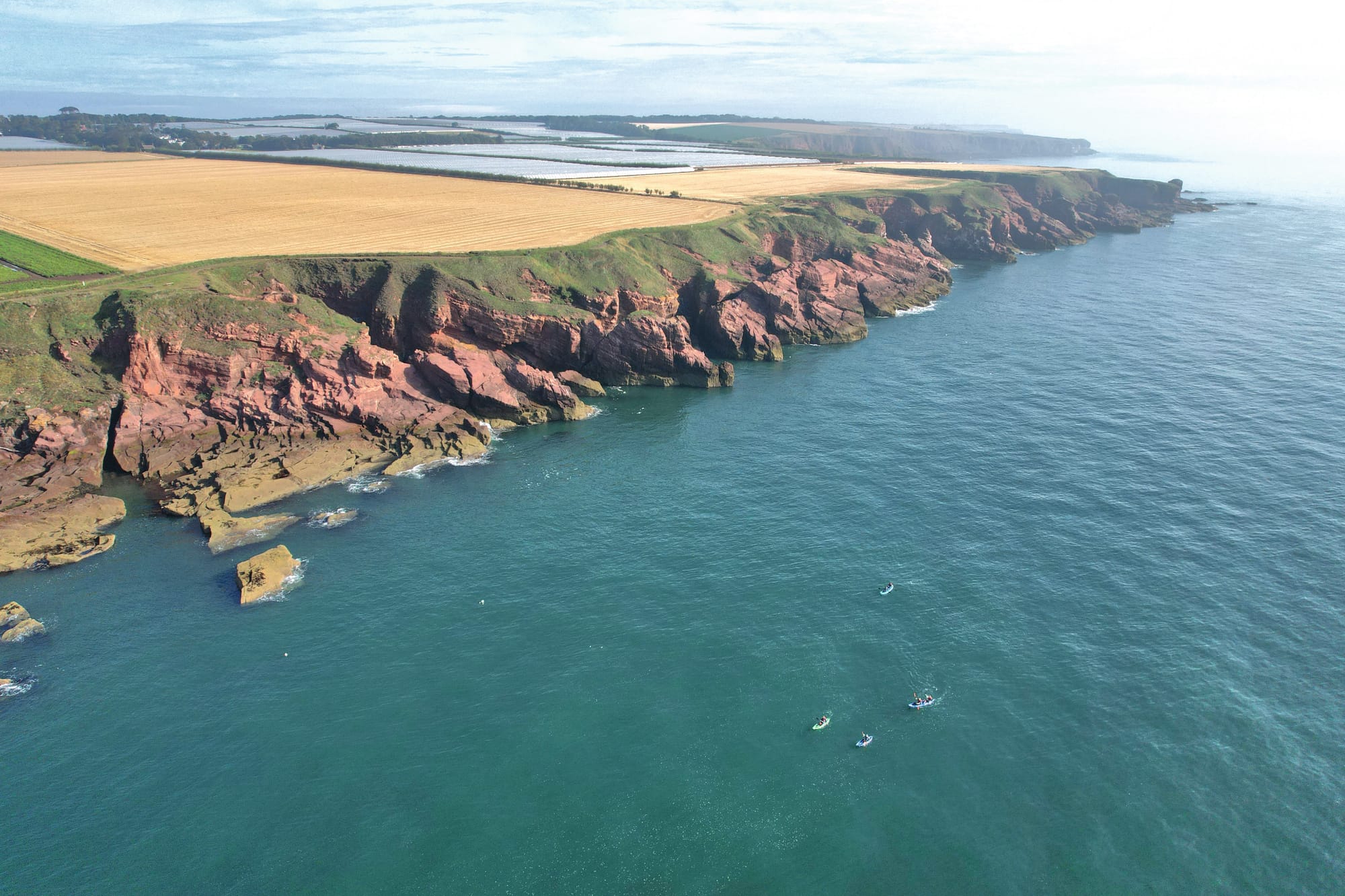 Aerial view of the sea and the red cliffs around the edge of the land.