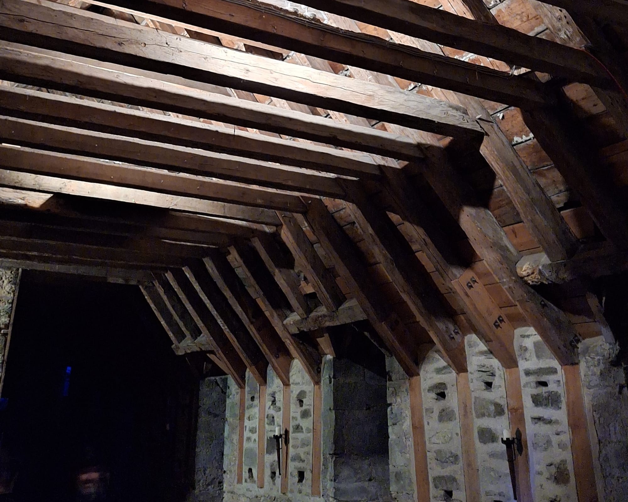 The stone walls and timber beams of a dark room in the castle. 