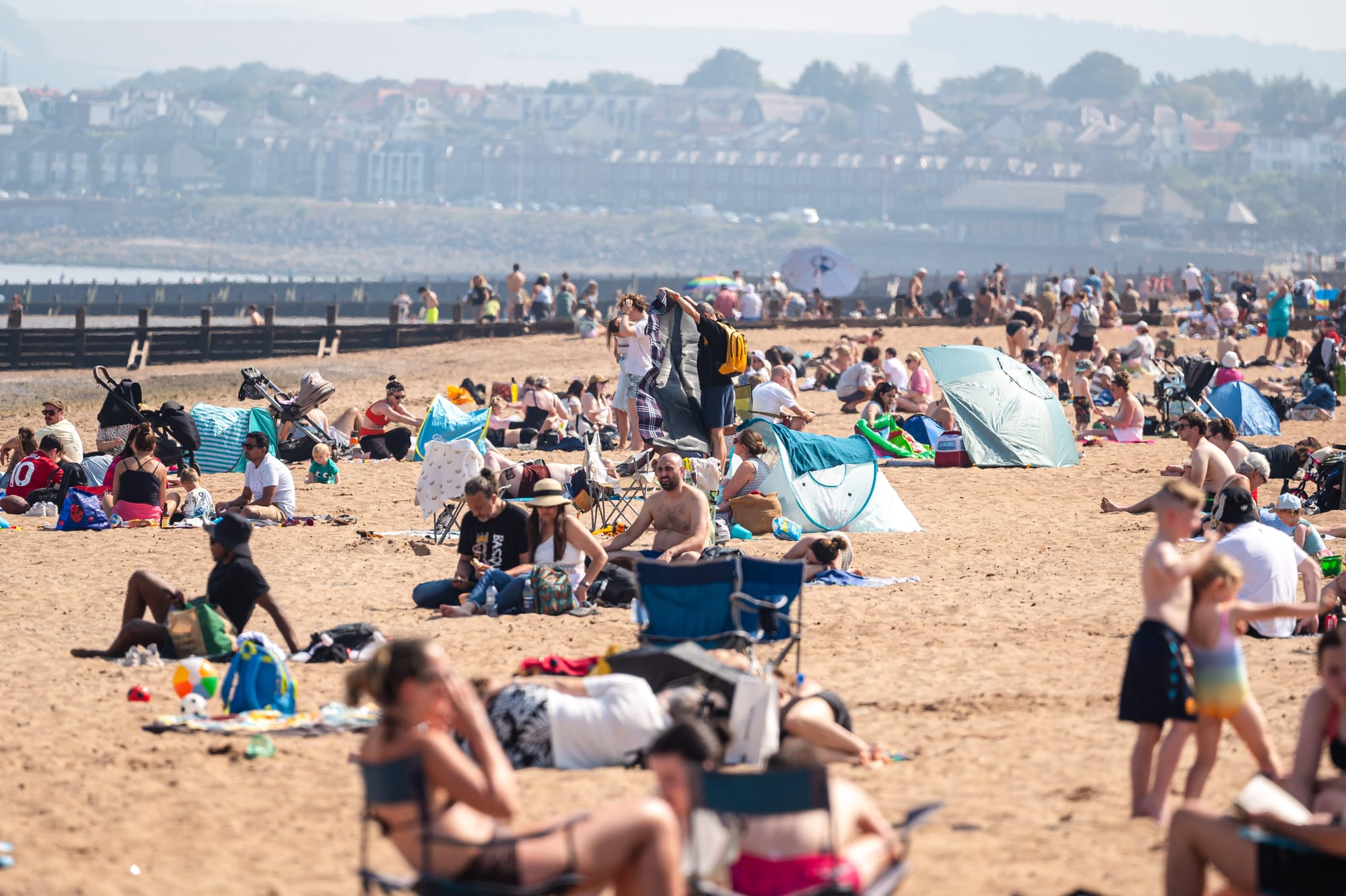 Portobello beach when very busy, with families settled across the sand.
