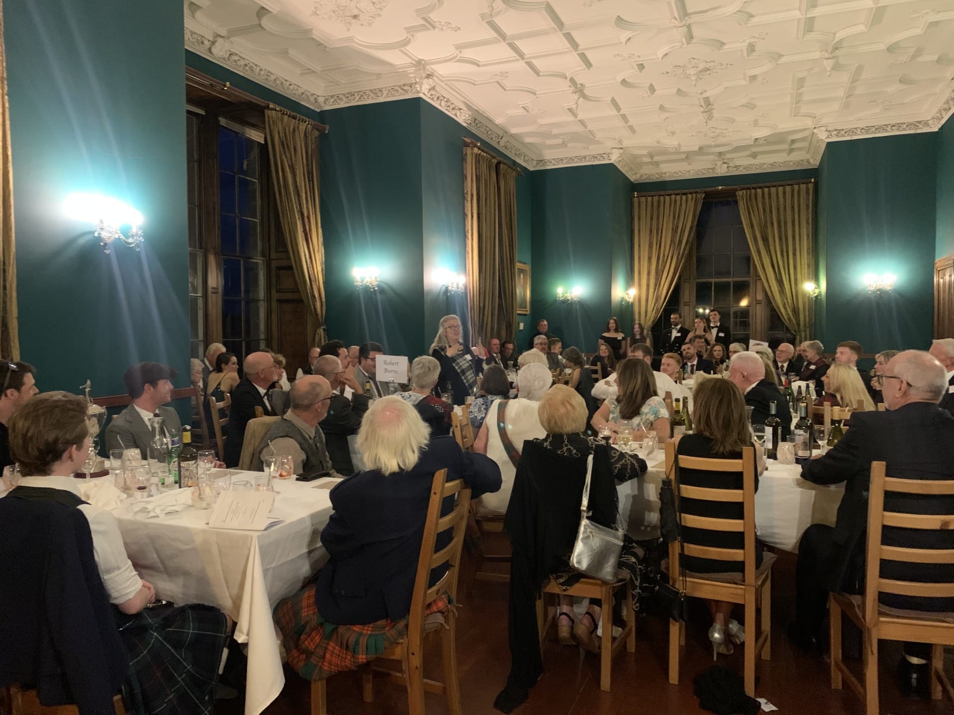 A busy room shows many tables of people dining.