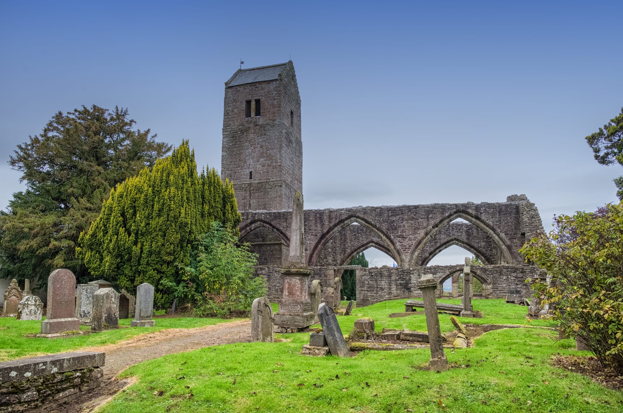 A ruined grey church with gravestones in the foreground.