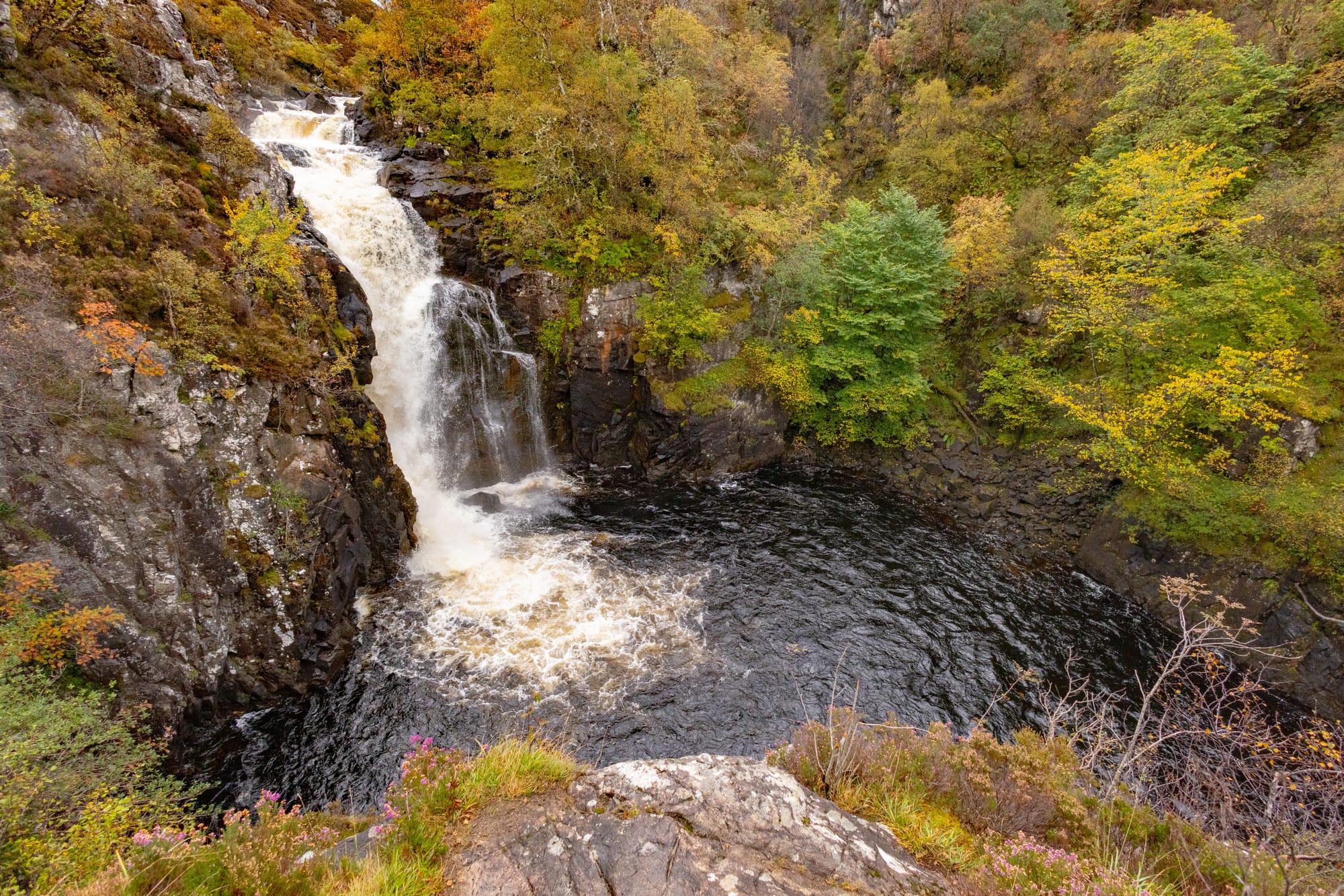 Looking down on Kirkaig Falls. Trees line the surrounding area.