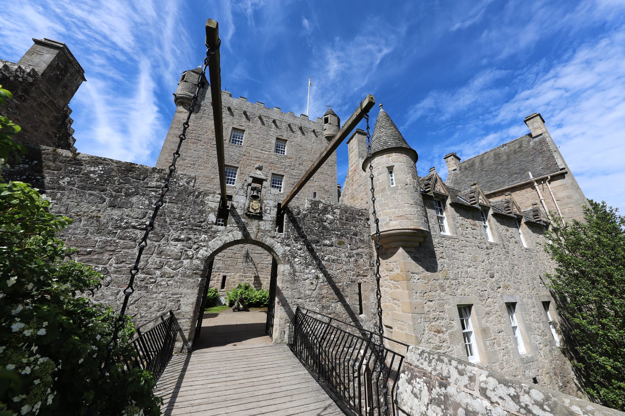 A drawbridge leading into a handsome looking castle with fine turrets.